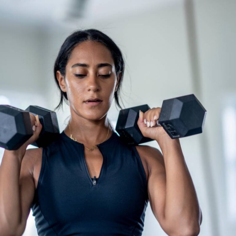 Woman lifting weights for strength training to help lessen sagging skin